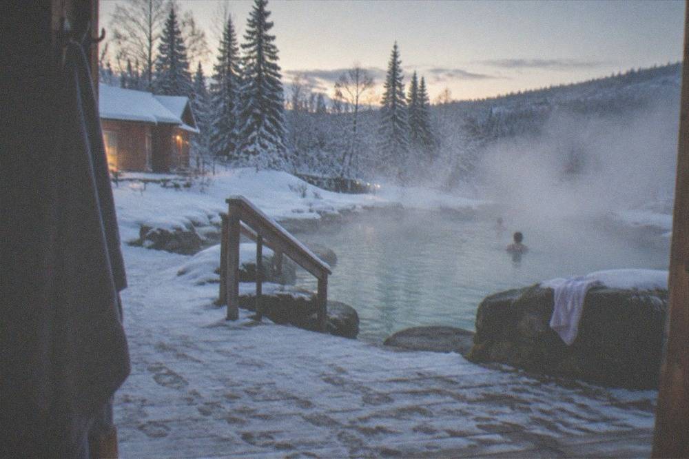 A steaming outdoor hot springs pool surrounded by snow at a resort near Fairbanks