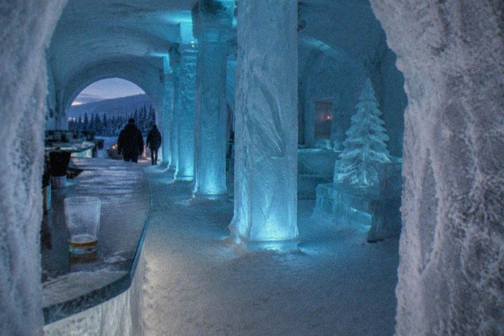 Blue-lit ice columns and frozen sculptures inside an ice museum gallery
