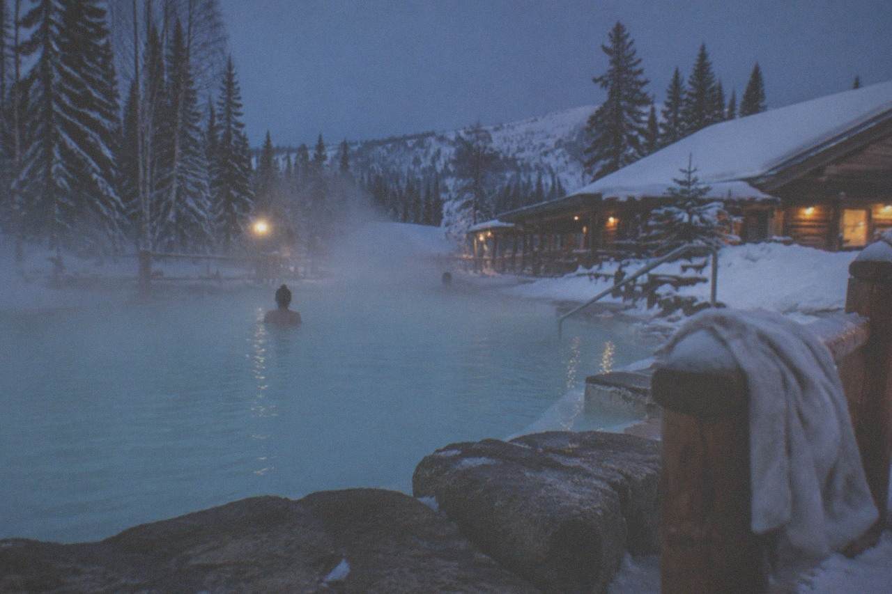 Steam rising from an outdoor hot springs pool under a dark winter sky