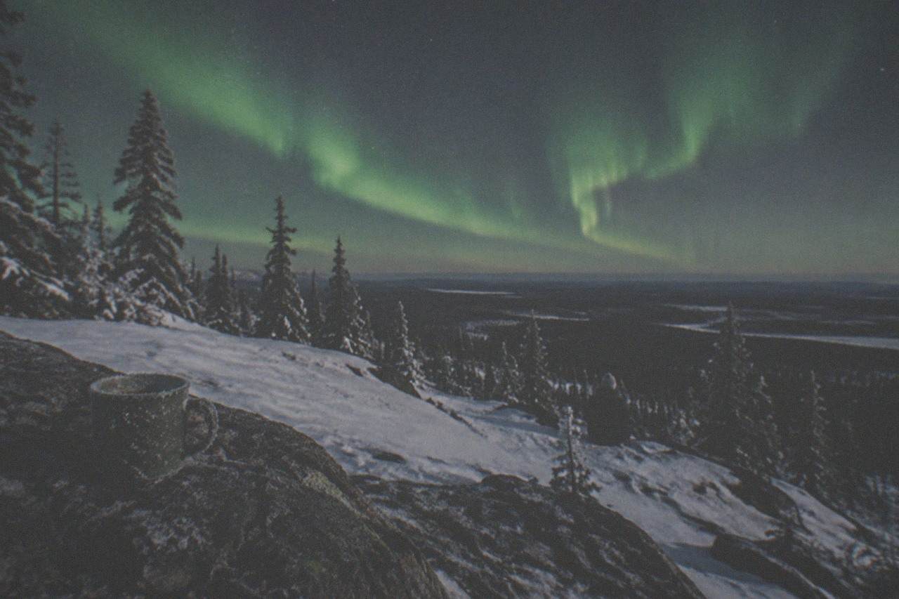 Green aurora bands above a snowy ridge outside Fairbanks under a starry night sky