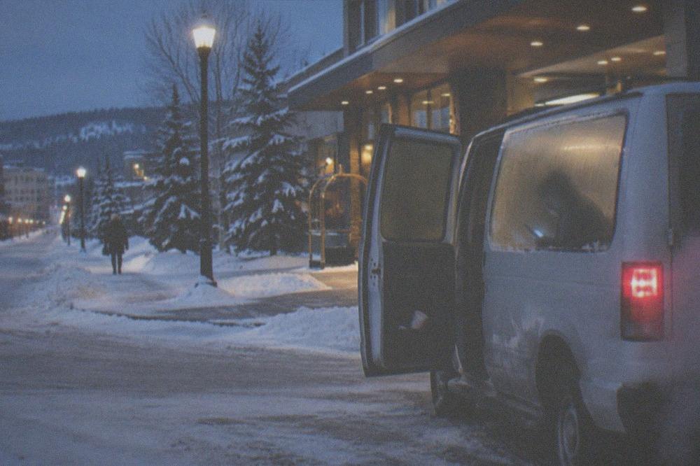 Traveler reading a phone screen inside a warm vehicle before a night tour departure