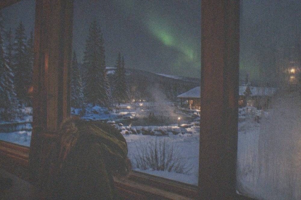 A heated lodge interior with large windows facing a dark snowy landscape at night