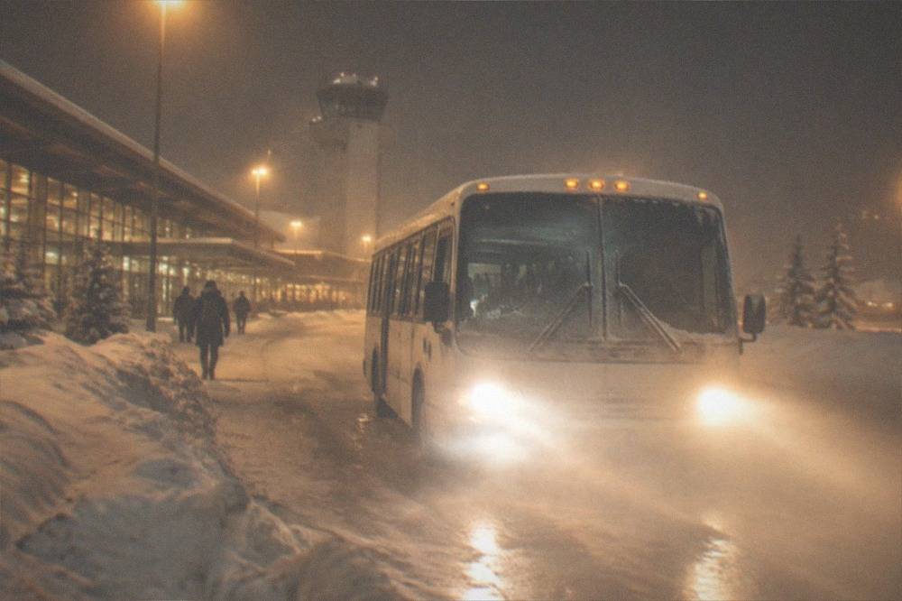 Car headlights on an icy road at night with snow banks on both shoulders
