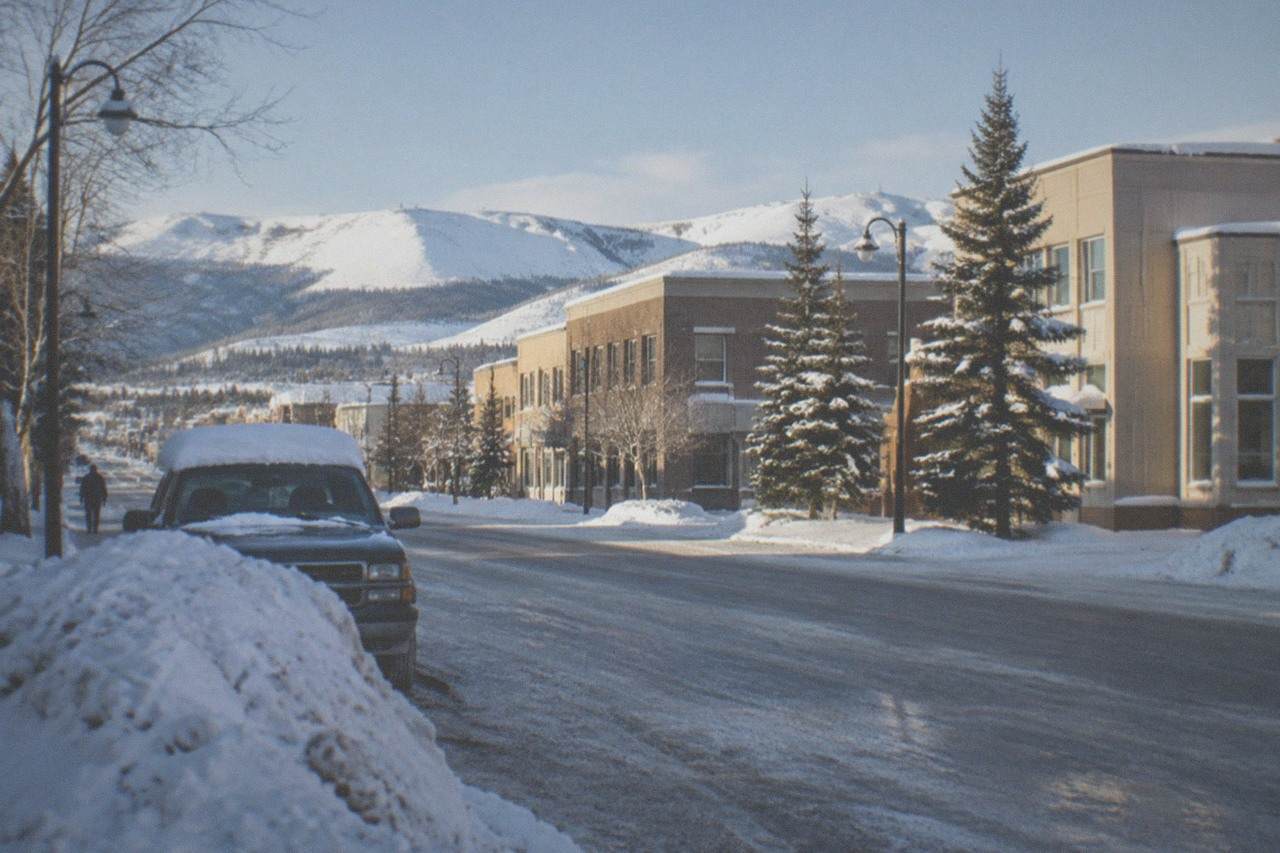 Snow-covered street in Fairbanks under a pale blue winter sky with low sun over the hills