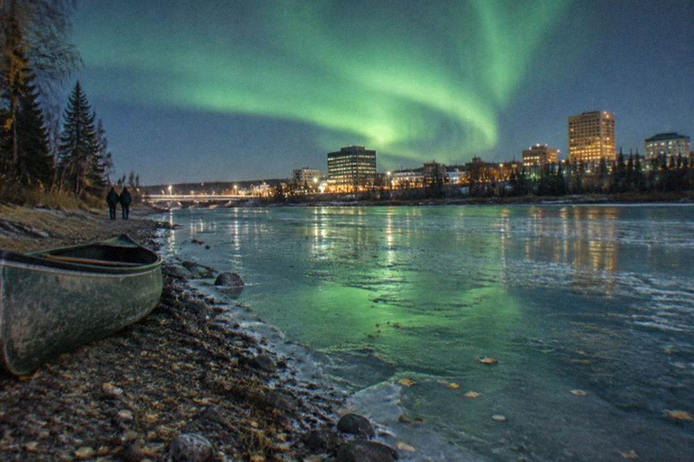 Deep green aurora glow reflected on the surface of a frozen river outside Fairbanks